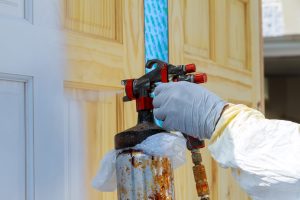 Hand with spray gun painting wooden door use for home decorated