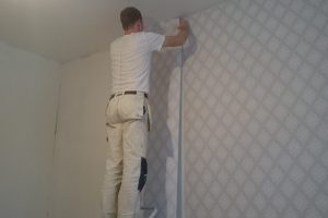 rear-view-man-applying-wallpaper-home